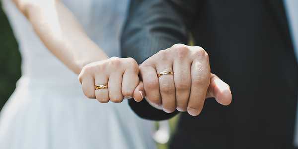 A couple showing their gold wedding rings.